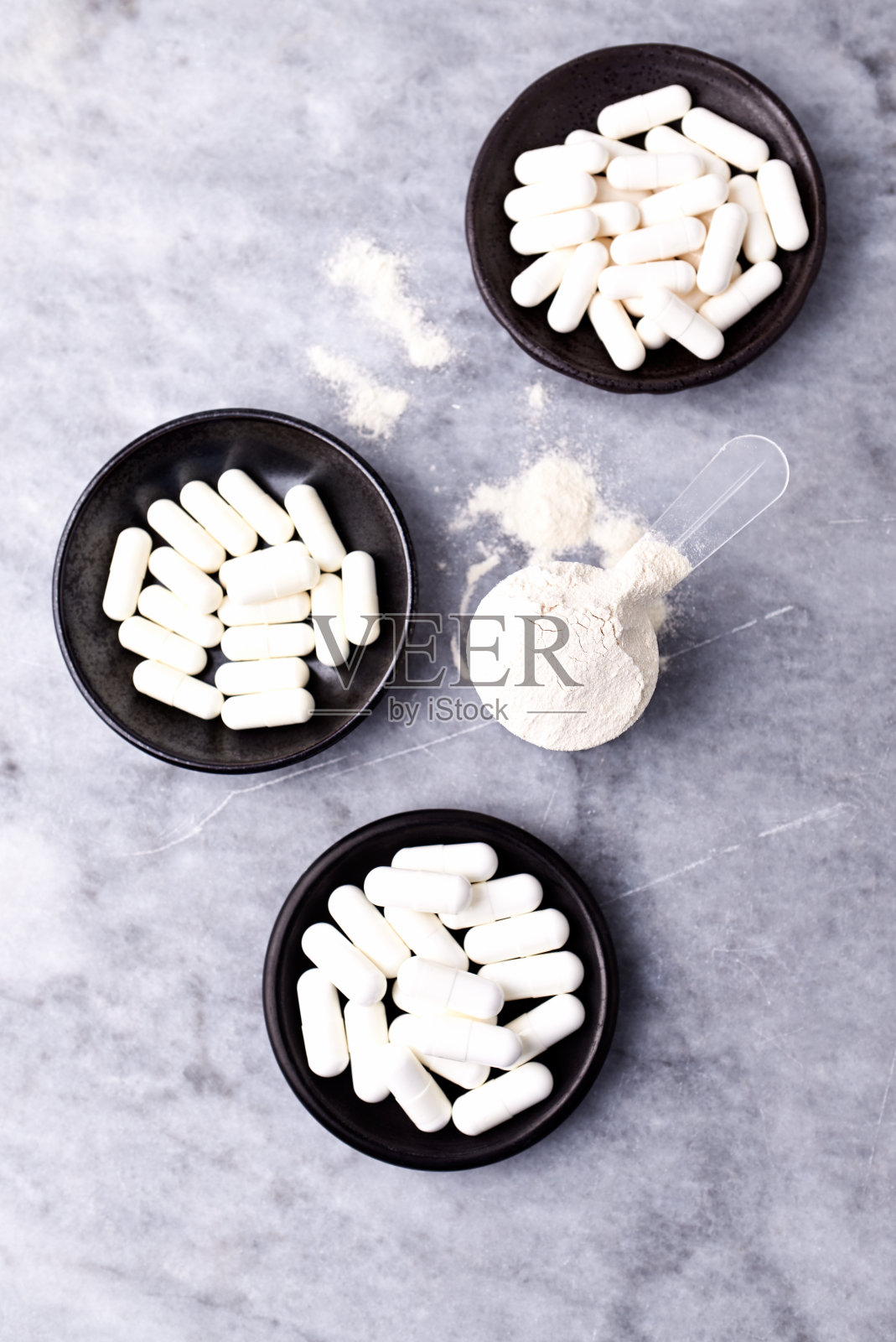 乳清蛋白,水解膠原I型,l -脯氨酸和l -賴氨酸膠囊勺。補充膠原蛋白的生產。明亮的石頭背景。直接上圖。副本的空間。